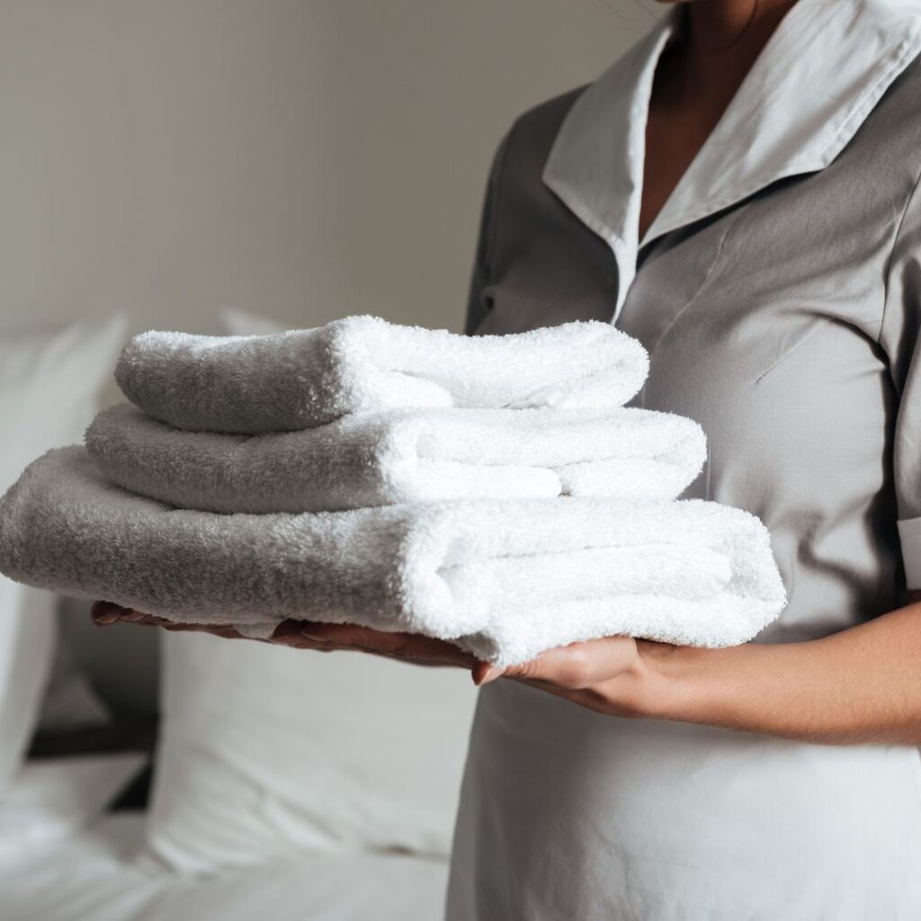housekeeper holding a stack of clean white towels